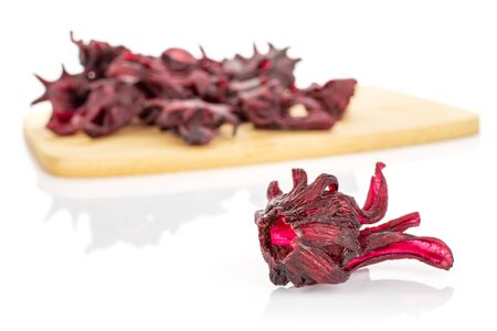 Lot of whole sweet red candied hibiscus one is aside and the rest is on bamboo cutting board isolated on white backgroundの写真素材