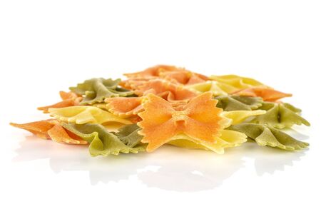 Lot of whole red, yellow and green uncooked farfalle isolated on white background