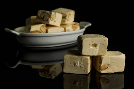 Lot of whole sweet white nougat in white oval ceramic bowl isolated on black glassの写真素材