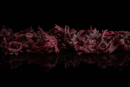 Lot of whole sweet red candied hibiscus isolated on black glassの写真素材