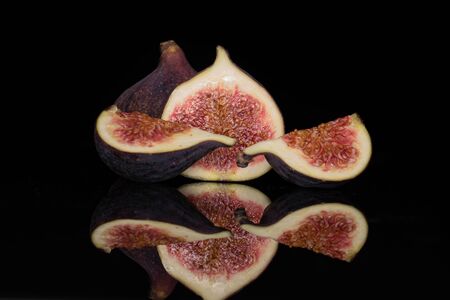 Group of one whole one half two slices of fresh fig fruit isolated on black glassの写真素材