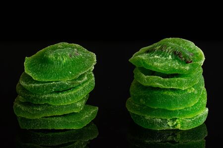 Group of ten slices of sweet green candied kiwifruit isolated on black glassの写真素材
