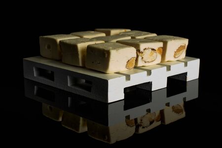 Group of nine whole sweet white nougat on white wooden pallet isolated on black glassの写真素材
