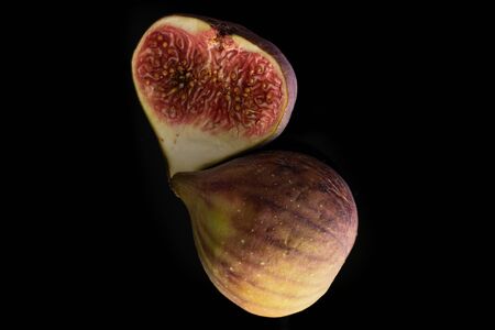 One half of fresh fig fruit flatlay isolated on black glassの写真素材