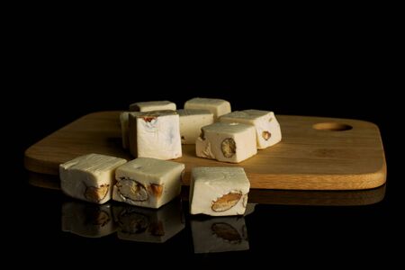 Lot of whole sweet white nougat on bamboo cutting board isolated on black glassの写真素材
