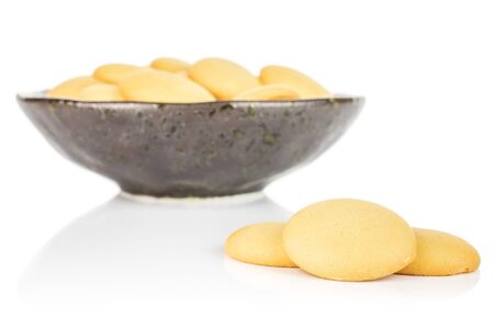 Lot of whole sweet golden sponge biscuit three are aside and the rest is in dark ceramic bowl isolated on white backgroundの写真素材