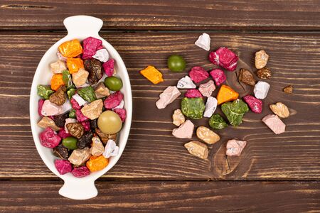 Lot of whole sweet chocolate stone in white oval ceramic bowl flatlay on brown woodの写真素材