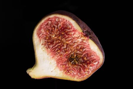 One half of fresh fig fruit macro flatlay isolated on black glassの写真素材