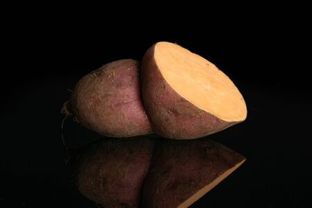 One half of fresh brown sweet potato isolated on black glassの写真素材
