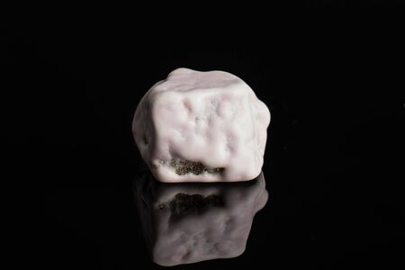One whole white sweet chocolate stone isolated on black glassの写真素材