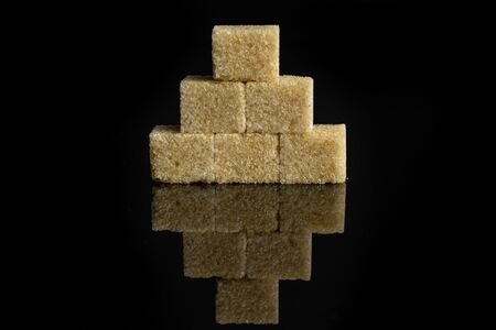 Group of six whole sweet brown sugar cube isolated on black glassの写真素材