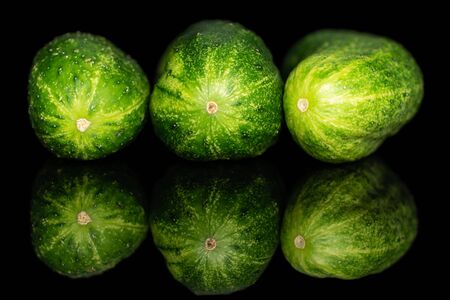 Group of three whole fresh green pickling cucumber in row isolated on black glassの写真素材