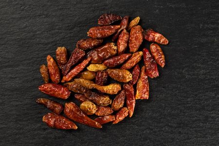 Lot of whole dry red chili pepper peperoncino heap flatlay on grey stone