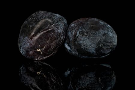 Group of two whole drying dark blue plum isolated on black glassの写真素材