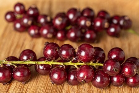 Lot of whole fresh dark redcurrant two clusters with braided rattan behind