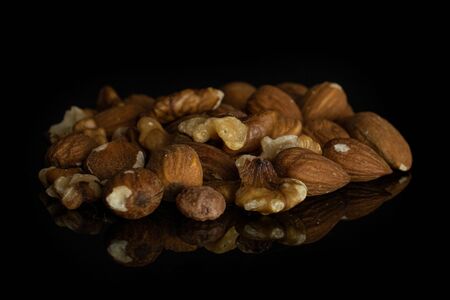 Lot of whole brown almond nut heap isolated on black glass