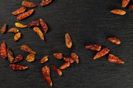 Lot of whole dry red chili pepper peperoncino flatlay on grey stone