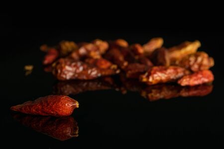Lot of whole dry red chili pepper peperoncino isolated on black glass