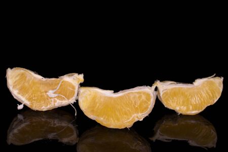 Group of three pieces of fresh bright orange isolated on black glassの写真素材