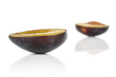 Group of two halves of fresh purple plum front focus isolated on white backgroundの写真素材