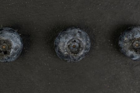 Group of three whole fresh blue blueberry flatlay on grey stone