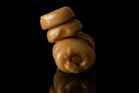 Lot of whole dark caramel brown candy heap isolated on black glassの写真素材