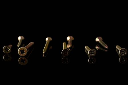 Group of nine whole metallic glossy bolt isolated on black glassの写真素材