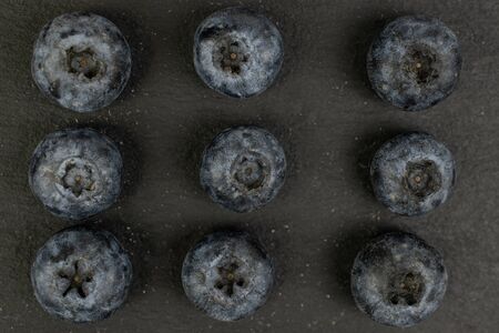 Group of nine whole fresh blue blueberry flatlay on grey stone