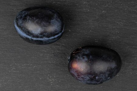 Group of two whole fresh purple plum flatlay on grey stoneの写真素材