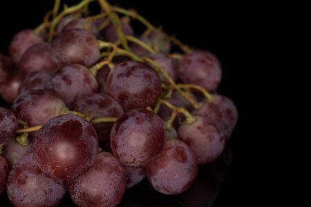 Lot of whole fresh purple grape rose isolated on black glassの写真素材