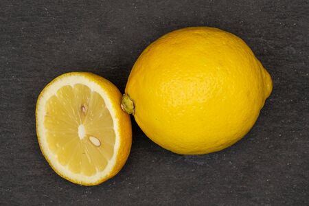 Group of one whole one half of fresh yellow lemon flatlay on grey stoneの写真素材