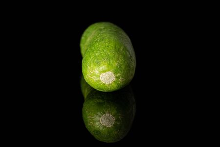 One whole mini green cucumber isolated on black glassの写真素材