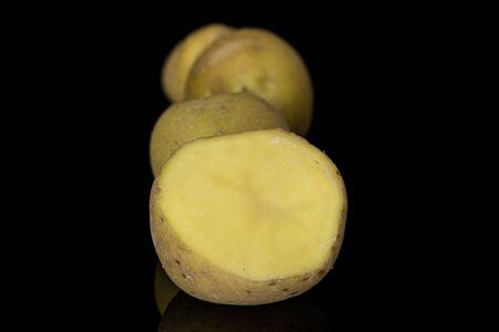Group of three whole one half of raw brown potato isolated on black glassの写真素材