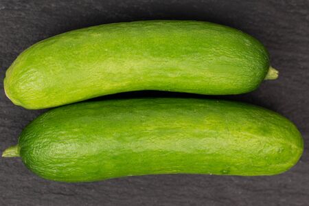 Group of two whole mini green cucumber flatlay on grey stoneの写真素材