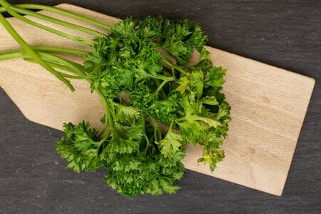 Lot of whole fresh green parsley on wooden cutting board flatlay on grey stoneの写真素材