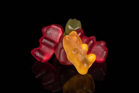 Group of five whole gummy bear isolated on black glass
