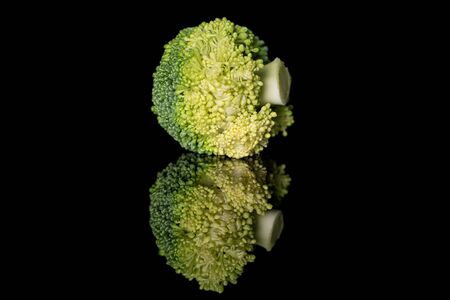 Whole fresh green broccoli isolated on black glassの写真素材