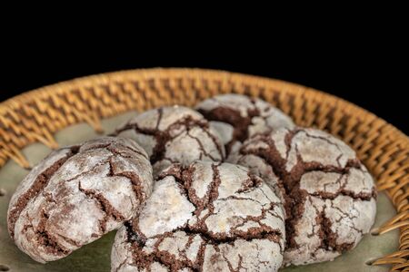 Group of five whole baked chocolate brownie cookie on plate with braided edge isolated on black...