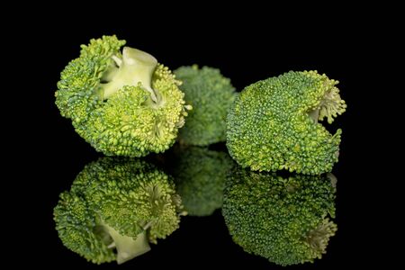 Group of three whole fresh green broccoli isolated on black glassの写真素材