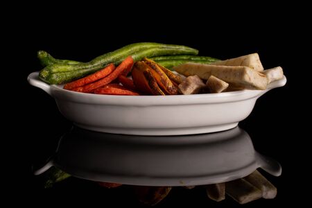 Lot of whole dry vegetable chip in white oval ceramic bowl isolated on black glassの写真素材