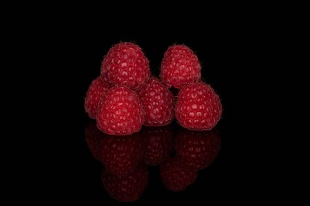Group of six whole fresh red raspberry isolated on black glassの写真素材