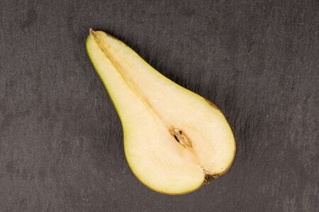 One half of fresh green pear flatlay on grey stone