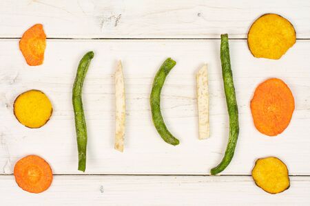 Lot of whole dry vegetable chip flatlay on white wood