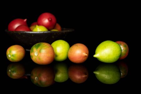 Lot of whole fresh tomato de barao on glazed bowl isolated on black glassの写真素材