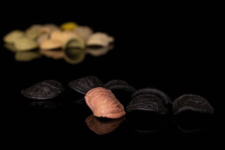 Lot of whole arranged colorful pasta orecchiette isolated on black glass