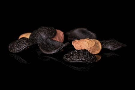 Lot of whole dark colorful pasta orecchiette heap isolated on black glass