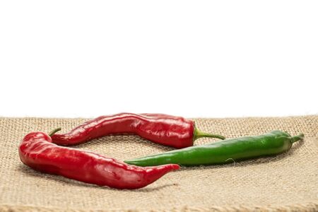 Group of three whole fresh hot pepper on jute cloth isolated on white background