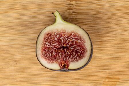 One half of sweet purple fig flatlay on light wood