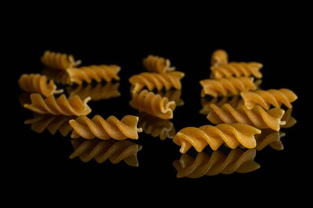 Lot of whole dry brown wholegrain fusilli isolated on black glassの写真素材