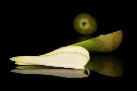 Group of one whole one half two slices of fresh green pear isolated on black glassの写真素材